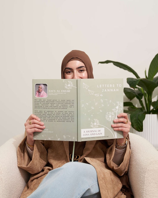 Person holding a book titled 'Letters to Zannah' in a cozy indoor setting with a plant in the background.