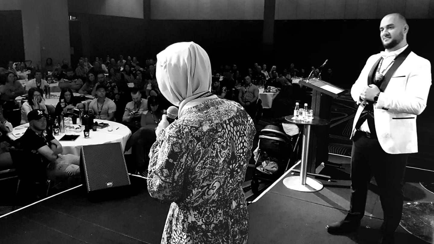A man standing looking at his wife while doing speech in an event