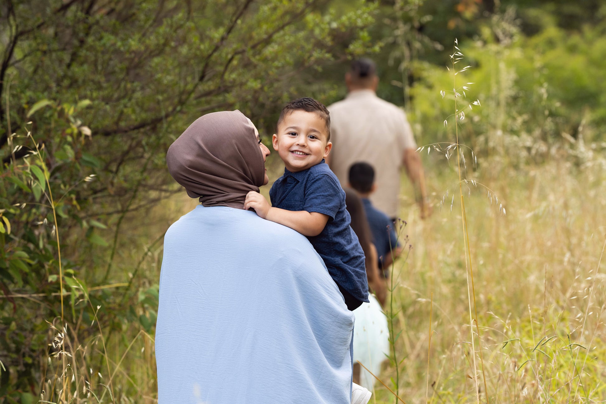 A child being counseled outdoors by an adult, with a natural background.