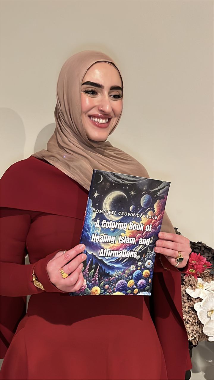 Woman holding a coloring book titled 'A Coloring Book of Healing, Islam, and Affirmations' against a neutral background.